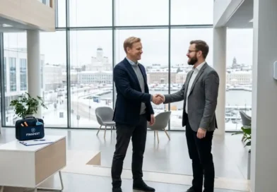 Two business professionals shaking hands inside a modern Finnish office building with pest control equipment and an indoor air quality monitor visible in the background, representing the Anticimex Oy and Indoor Quality Service Oy acquisition strategy.