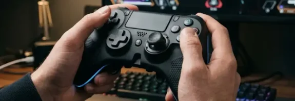 A gamer holding the Under Growth Games UGGControMan Controller in front of a gaming monitor