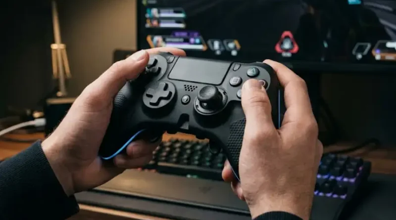 A gamer holding the Under Growth Games UGGControMan Controller in front of a gaming monitor